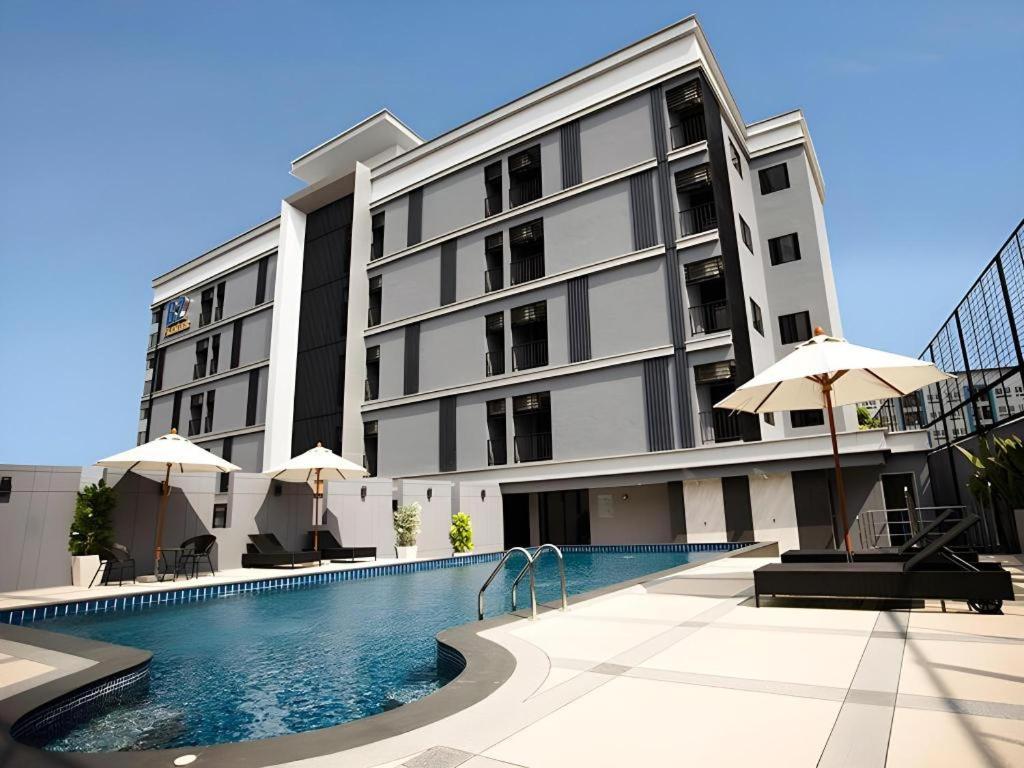 a large building with a swimming pool in front of it at B2 Amata Nakorn Premier Hotel in Ban Chak Samo