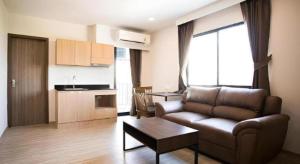 a living room with a couch and a table and a kitchen at B2 Amata Nakorn Premier Hotel in Ban Chak Samo