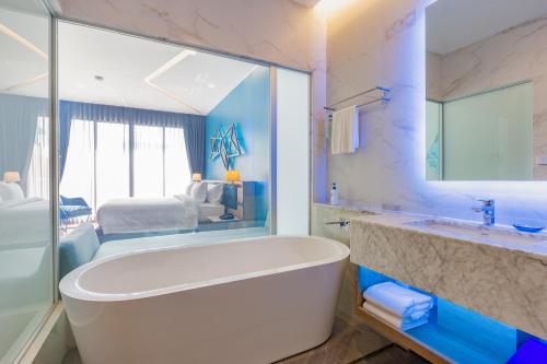 A bathroom with a large tub and a bedroom at BlueSotel SMART Krabi Aonang Beach - Adults only