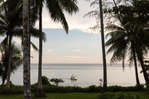 a man in a boat in the ocean between palm trees at Hideout Koh Kood in Ko Kood