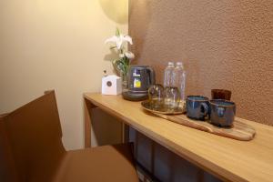 a table with cups and mugs and a vase of flowers at Mybed Chonburi in Ban Nong Tako