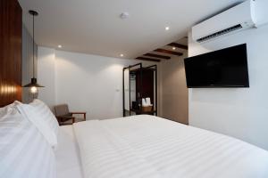 A bedroom with a white bed and a flat screen tv at P2 Wood Loft in Phi Phi Islands