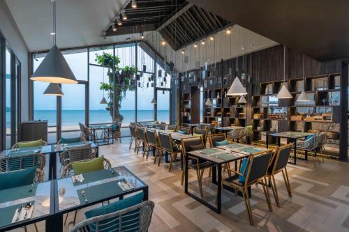 A restaurant with tables and chairs with the ocean in the background at U Jomtien Pattaya