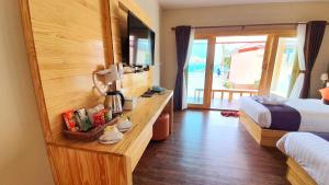 a hotel room with a bedroom with a bed and a television at Zodiac Seesun Resort in Koh Lipe